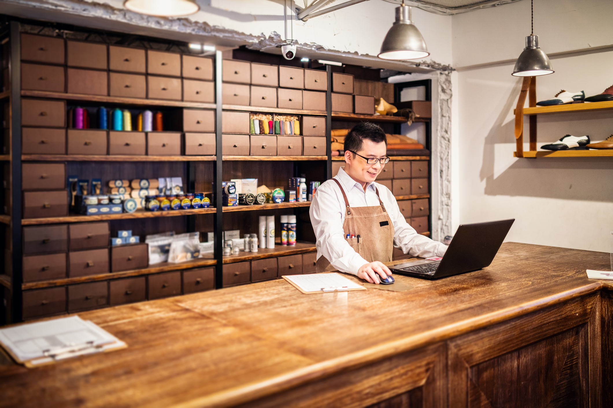 Tailor uses computer while standing in his shop